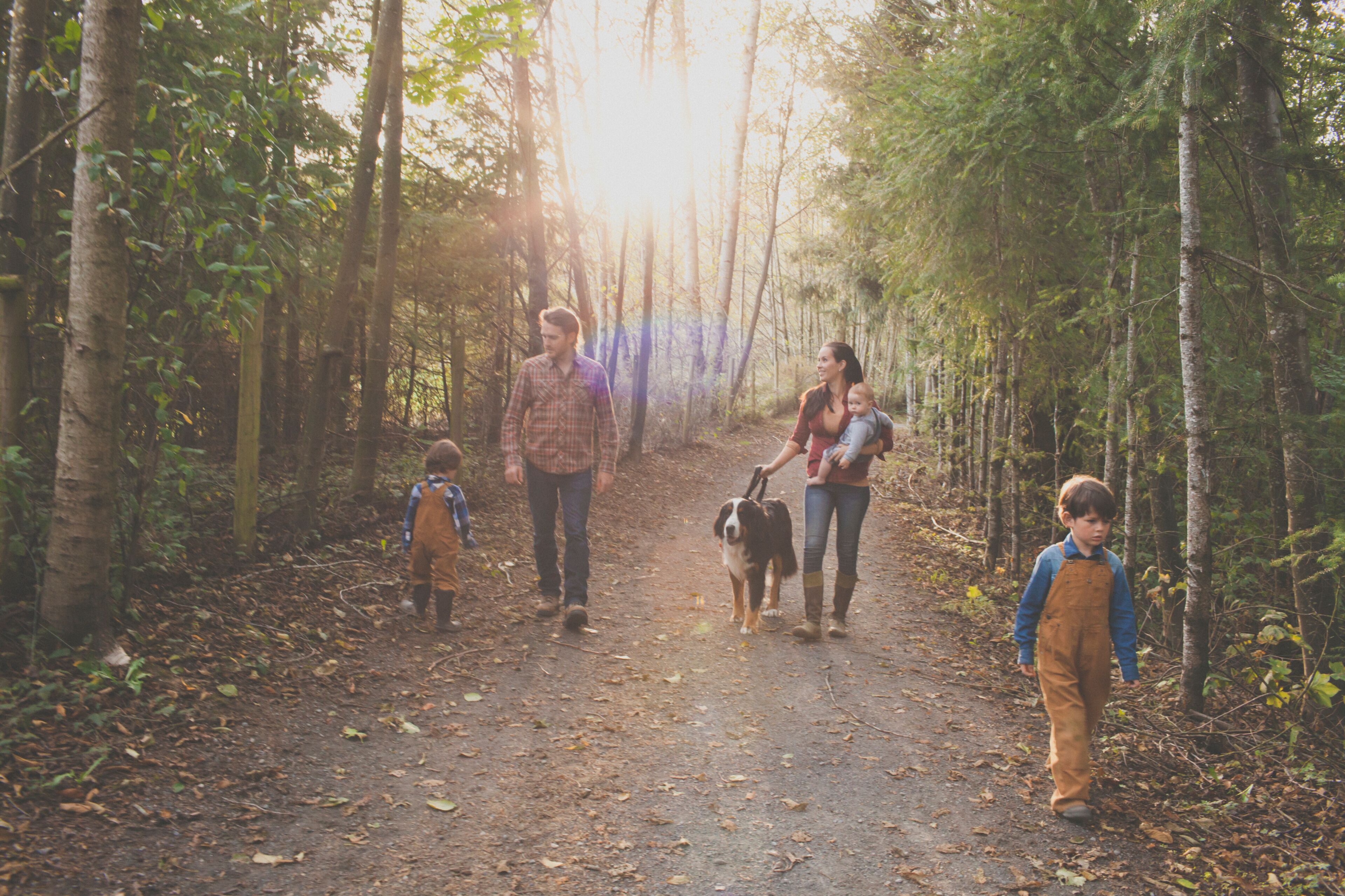 A family of five with a dog enjoy a morning walk on a gravel path at a local park.