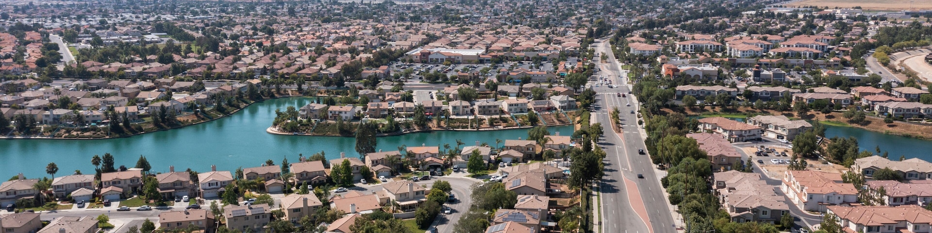 A residential area with a river, houses, and mountains in the background.