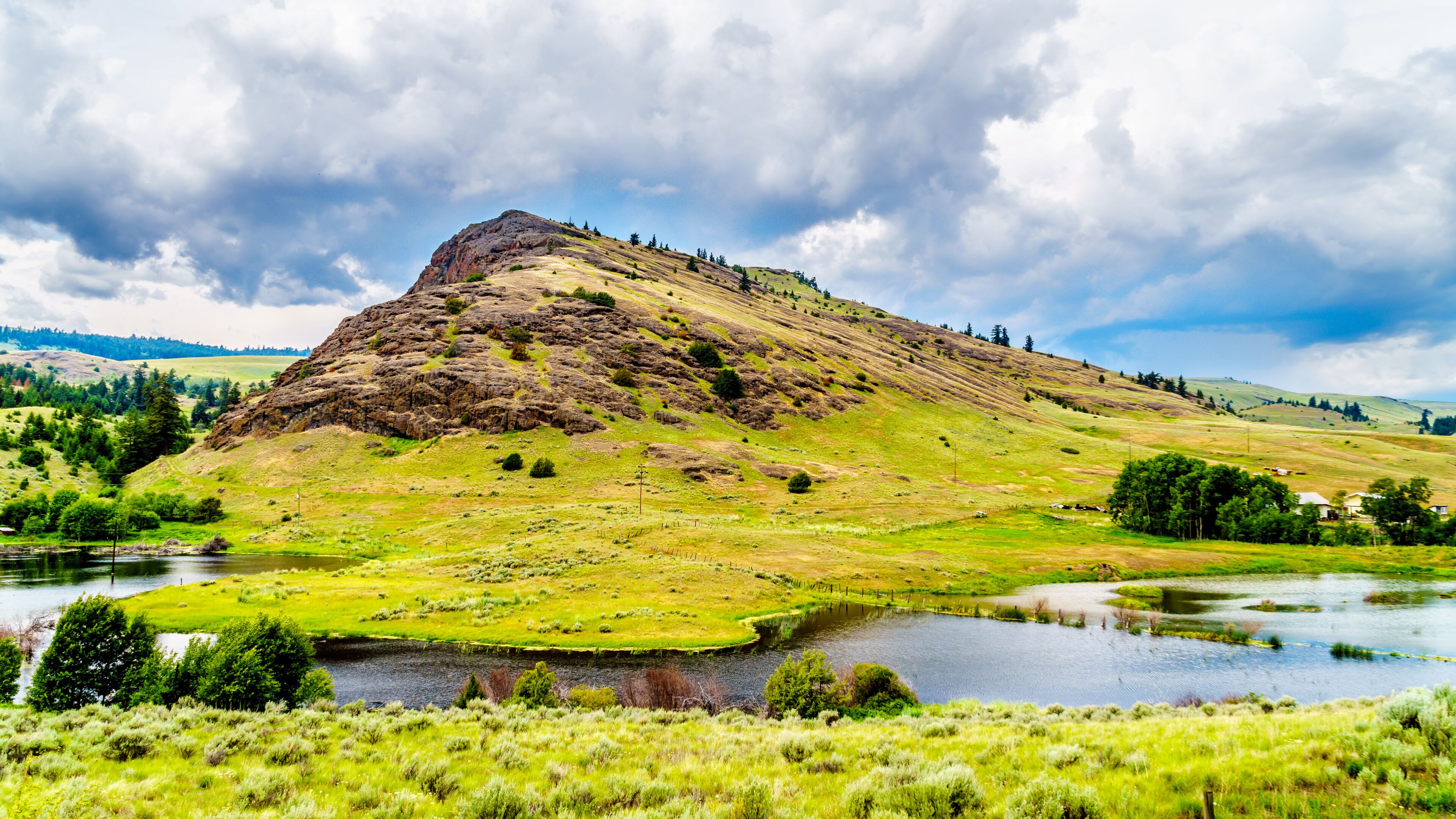 Rocky Mountain among the rolling hills in the Nicola Valley along Highway 5A between Merritt and Kamloops, British Columbia, Canada under dark cloudy skies