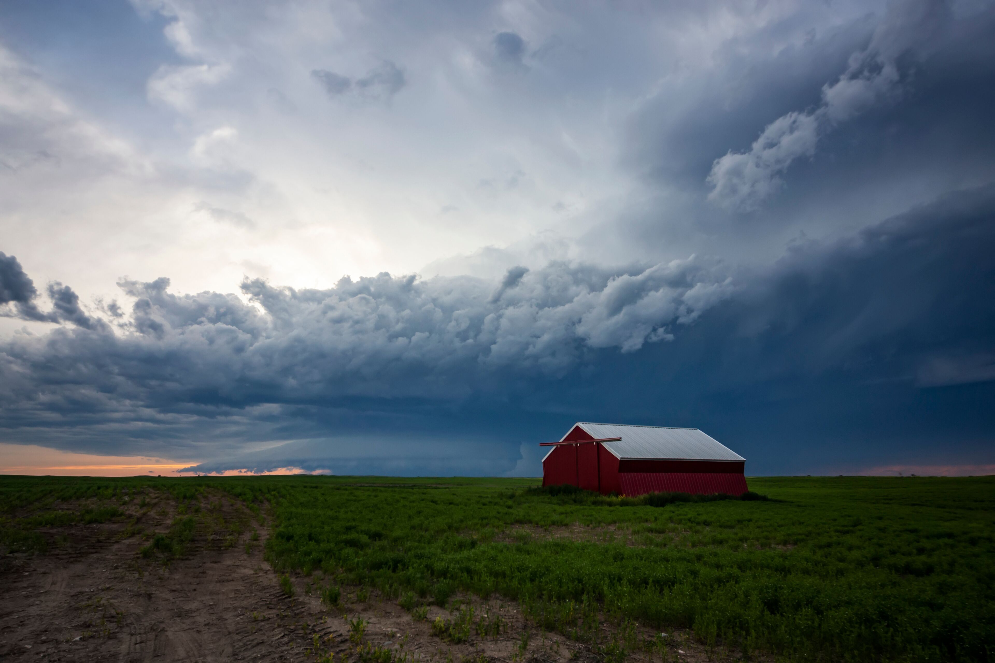 Storm cell moving overhead on farmland with a red barn; Moose Jaw, Saskatchewan, Canada