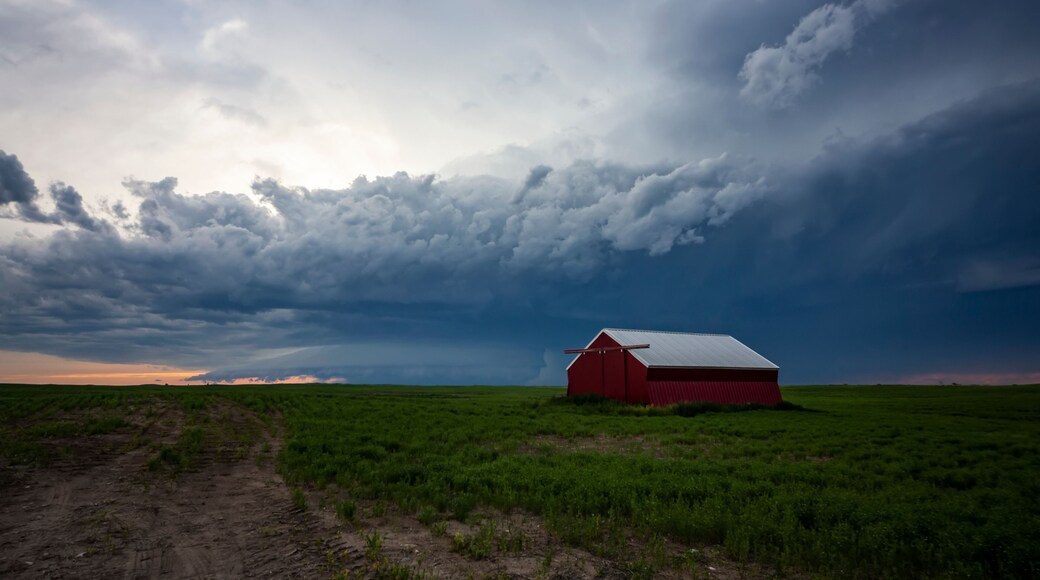 Storm cell moving overhead on farmland with a red barn; Moose Jaw, Saskatchewan, Canada
