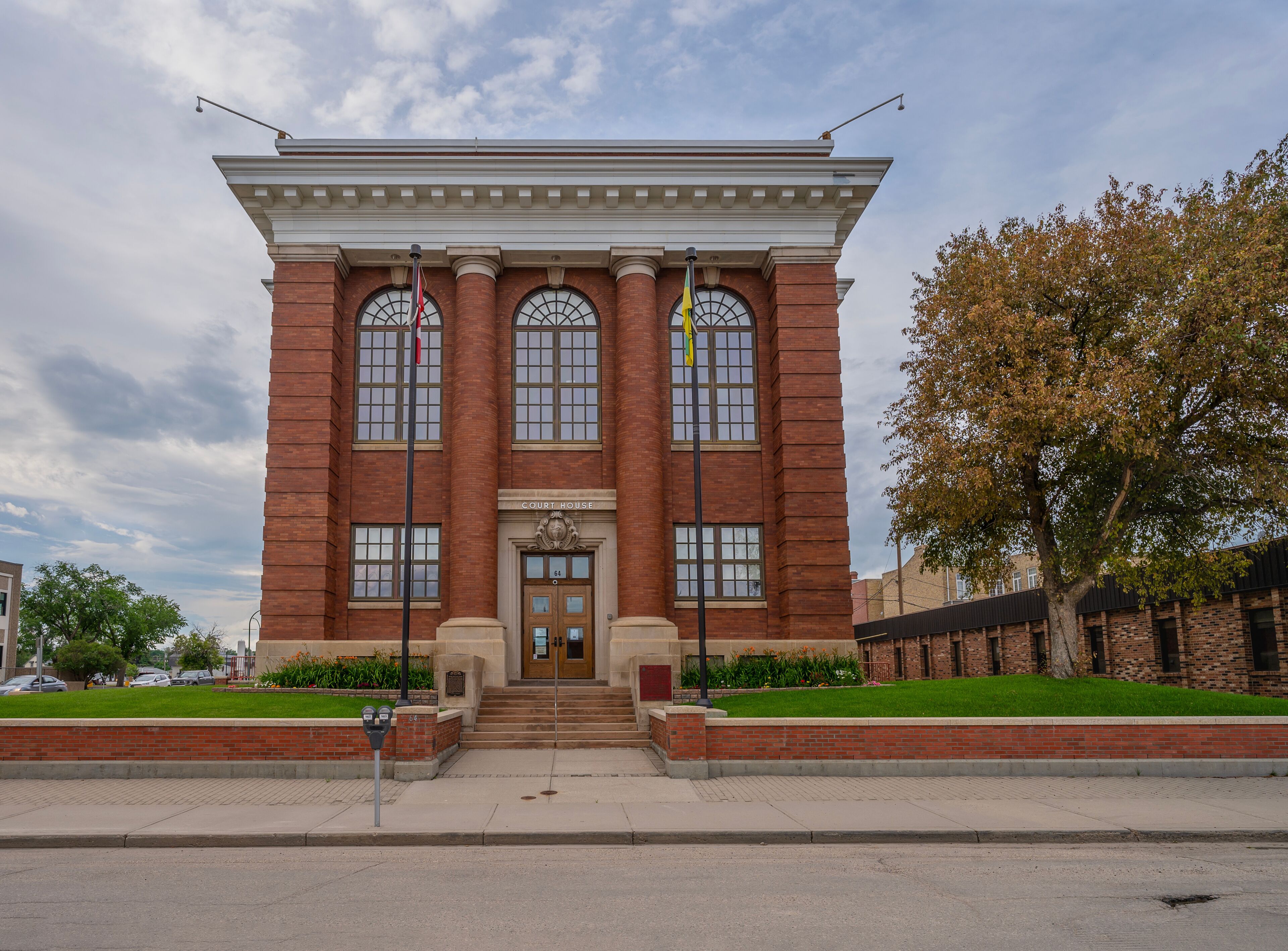 A brick courthouse with a central entrance, large windows, and a flagpole.