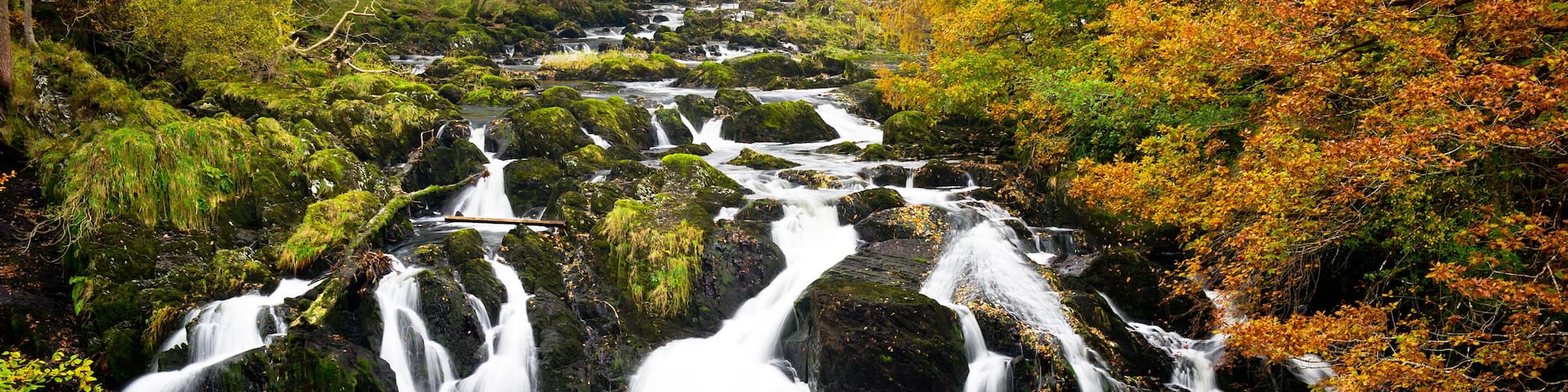 A multi-tiered waterfall surrounded by autumn foliage.