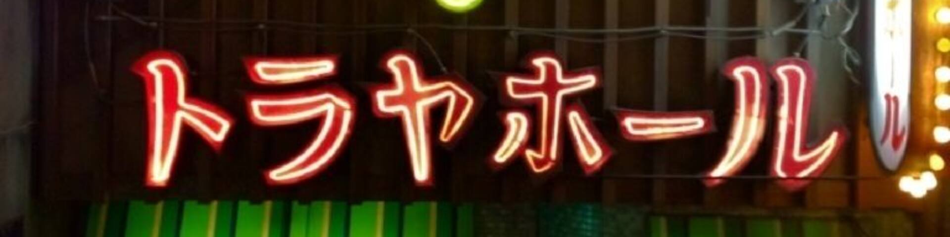 A neon sign with Japanese characters and a green awning.