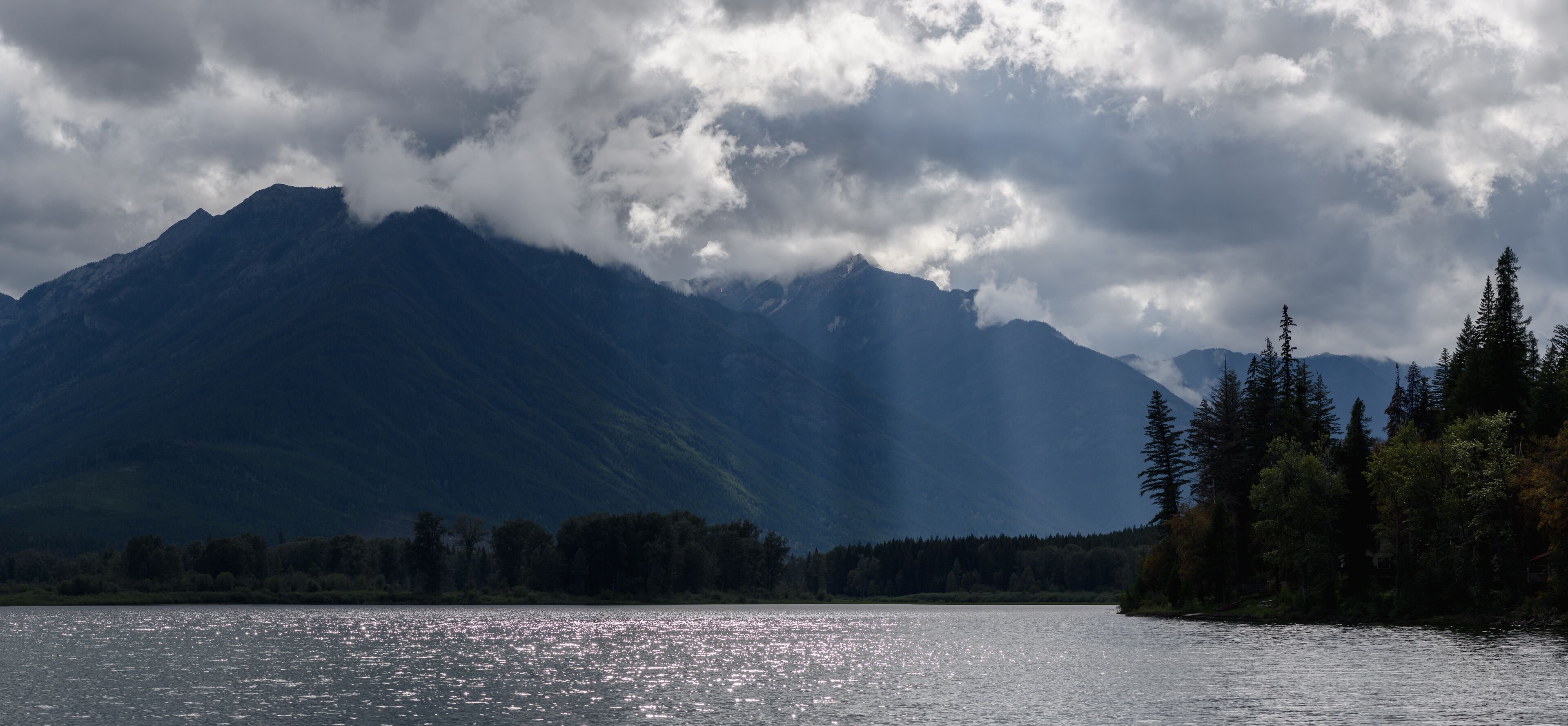 A lake with mountains in the background and trees along the shore.
