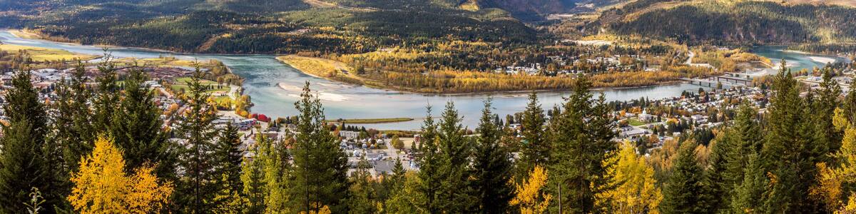 A mountainous landscape with a river, a town, and autumn foliage.