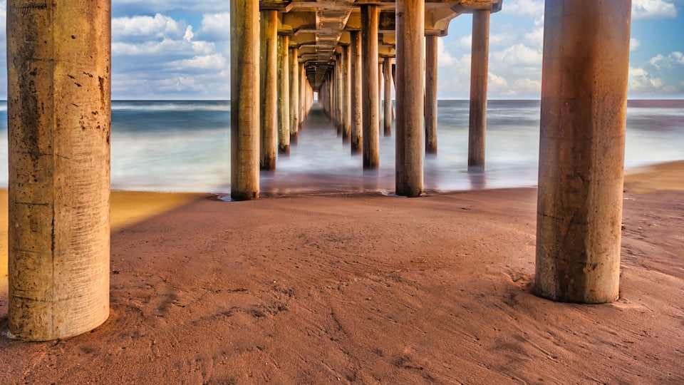 Long exposure captures slow moving waves under the Huntington Beach Pier in Huntington Beach, California
