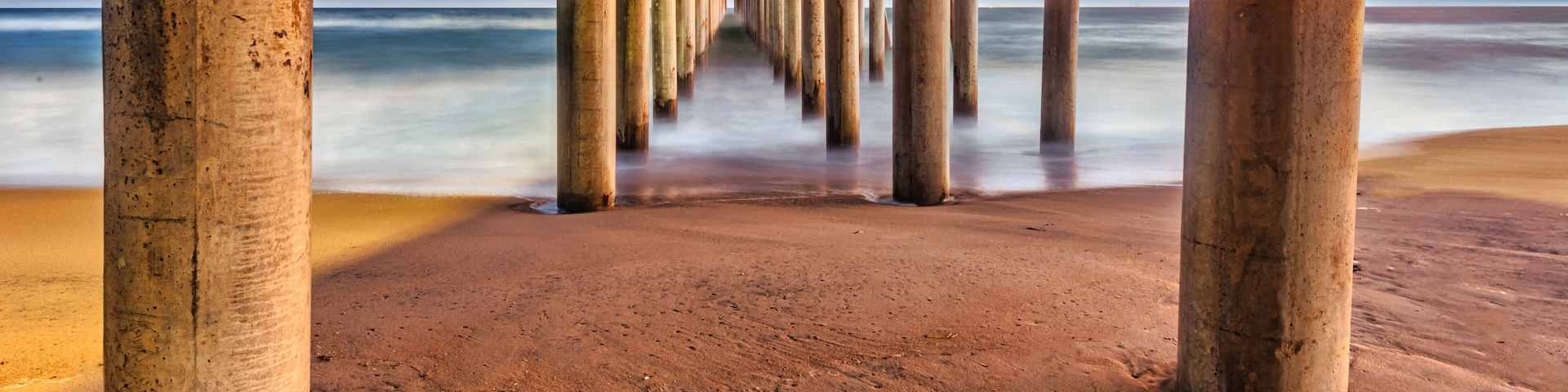 Long exposure captures slow moving waves under the Huntington Beach Pier in Huntington Beach, California