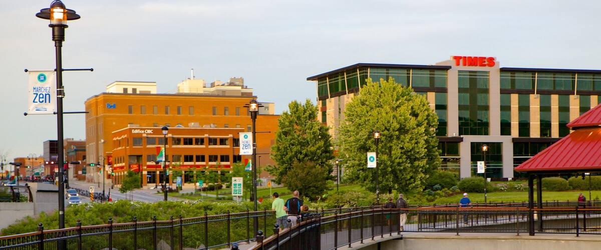 A pedestrian bridge over a canal with buildings, including a Times building, in the background.