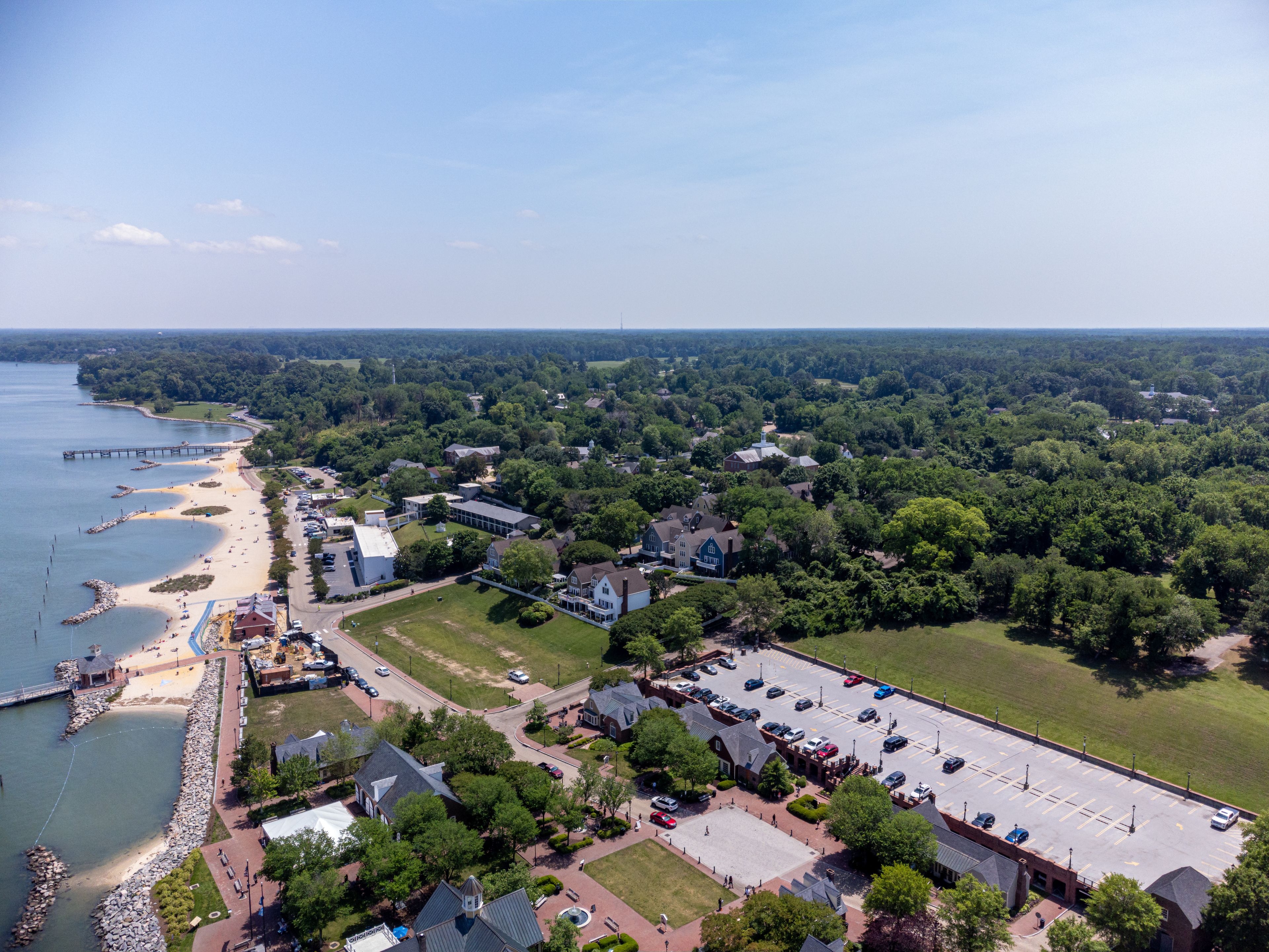 A coastal town with a beach, a pier, and a parking lot.