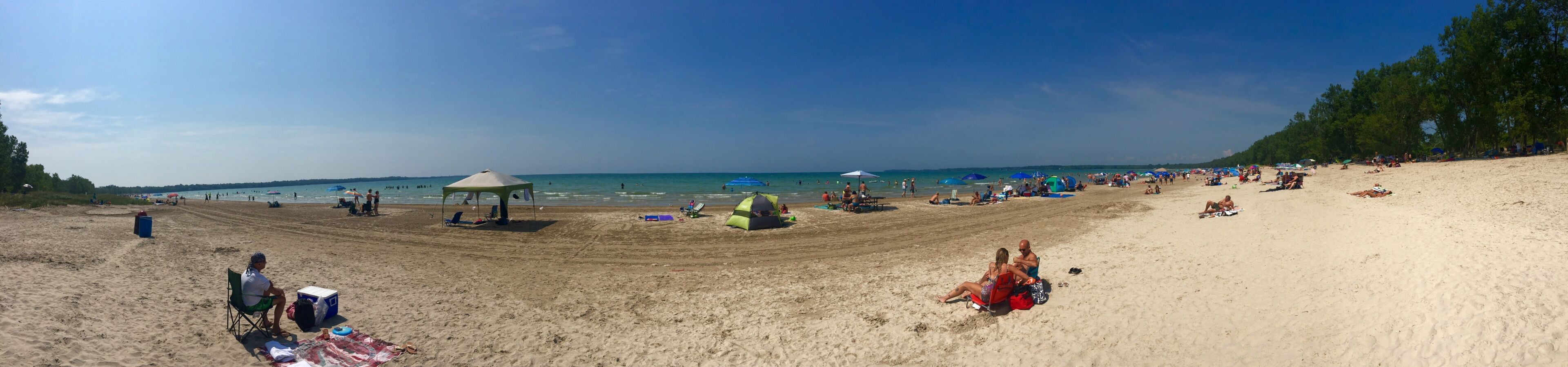 A beach with a gazebo, umbrellas, and people relaxing.