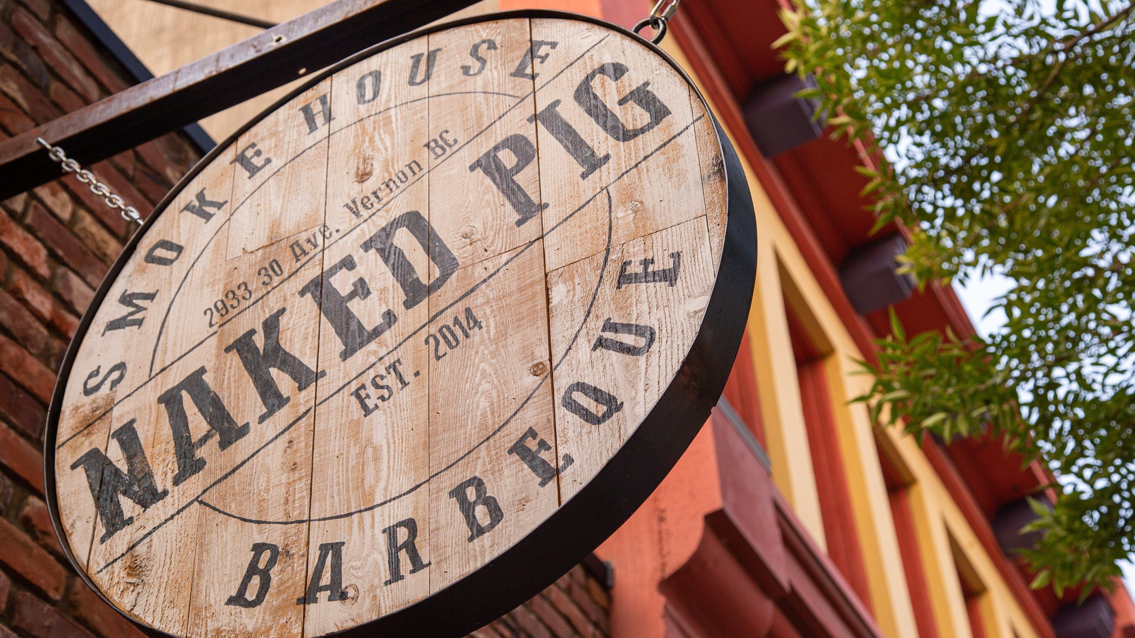 Un letrero de madera con el texto "Smoke House Naked Pig BBQ".