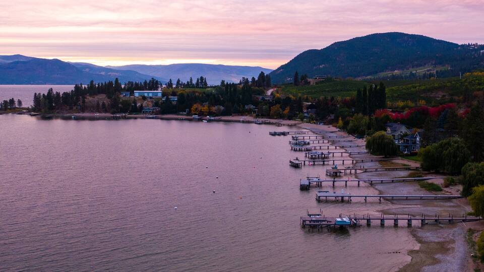 A lakeside view with docks, boats, and houses along the shore.