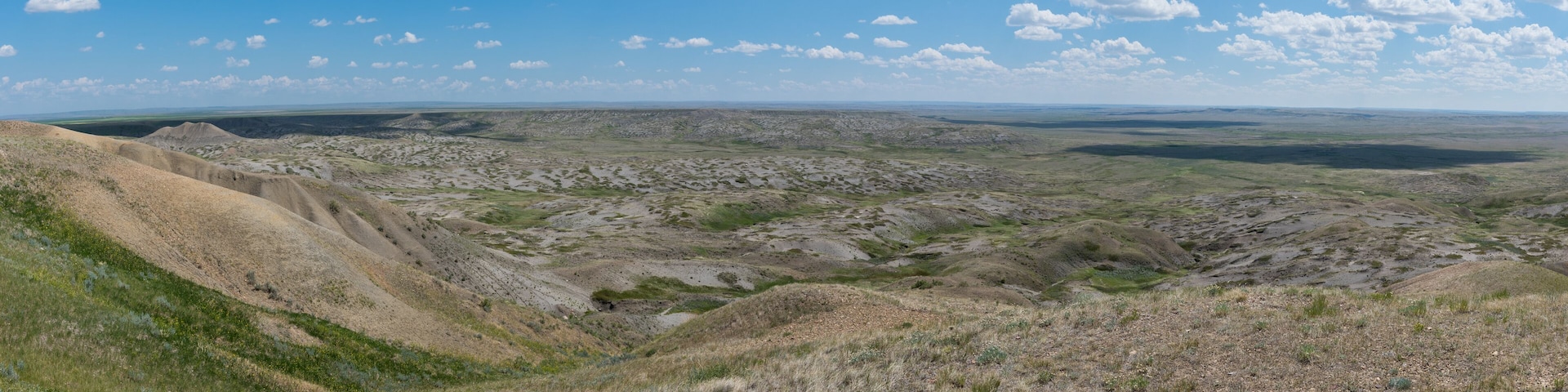 A vast, open landscape with rolling hills and sparse vegetation under a clear blue sky.