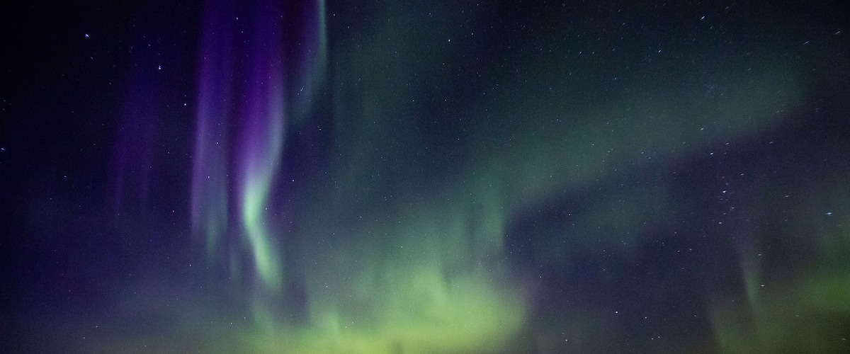 The Northern Lights over a calm body of water at night.