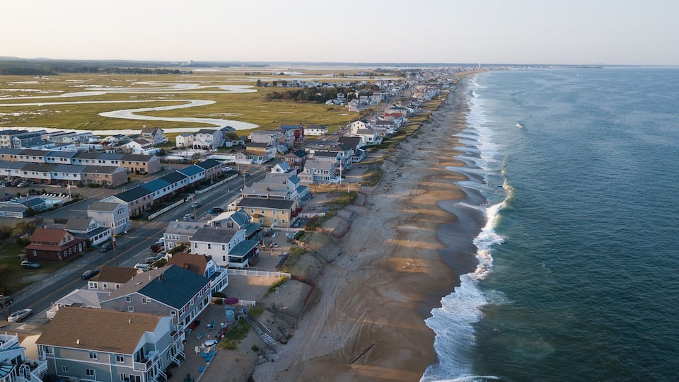 A coastal town with a beach, houses, and a road.