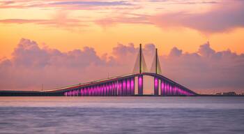 A bridge with two tall towers and a rainbow-colored lighting.