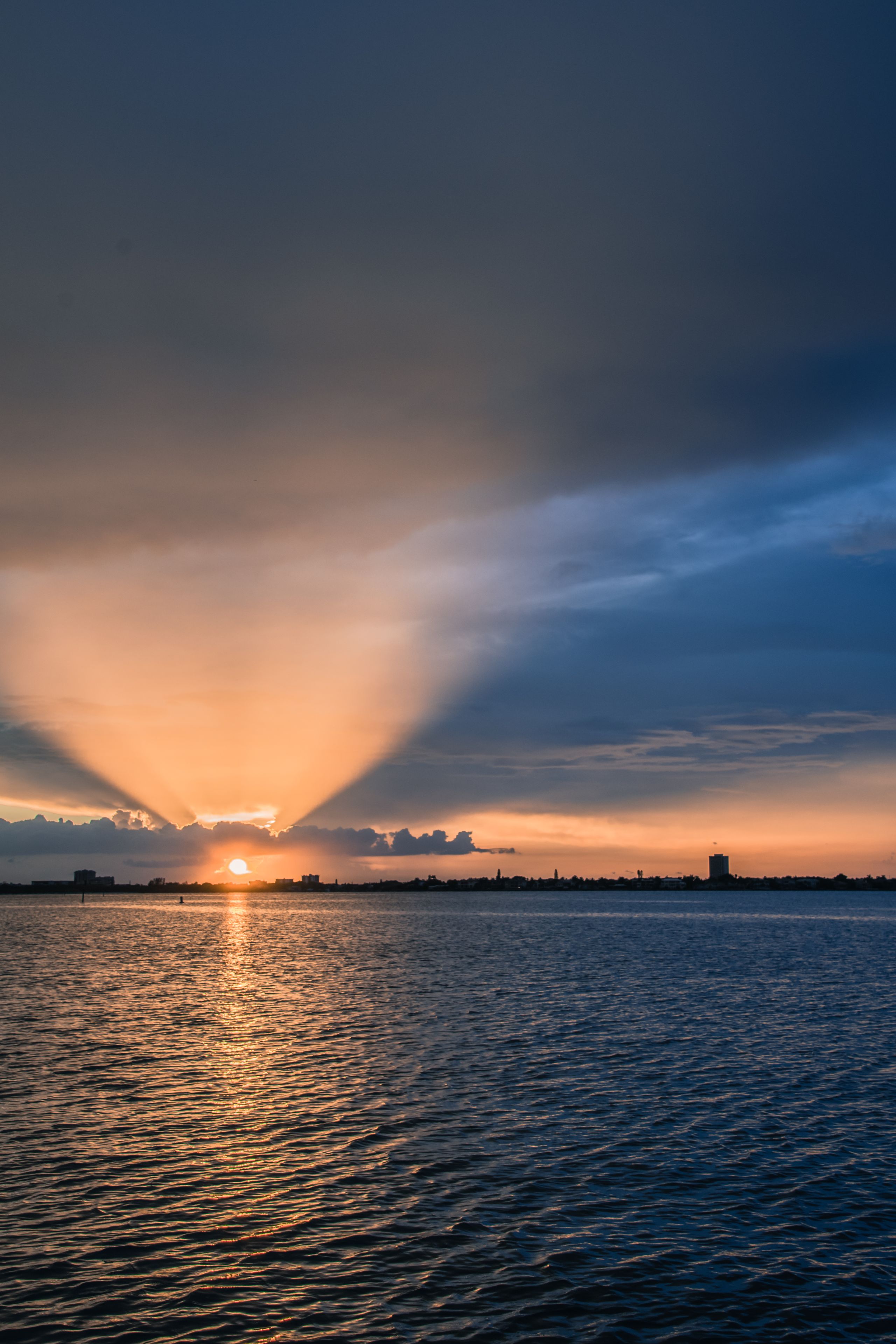A sunset over a body of water with a city skyline in the distance.