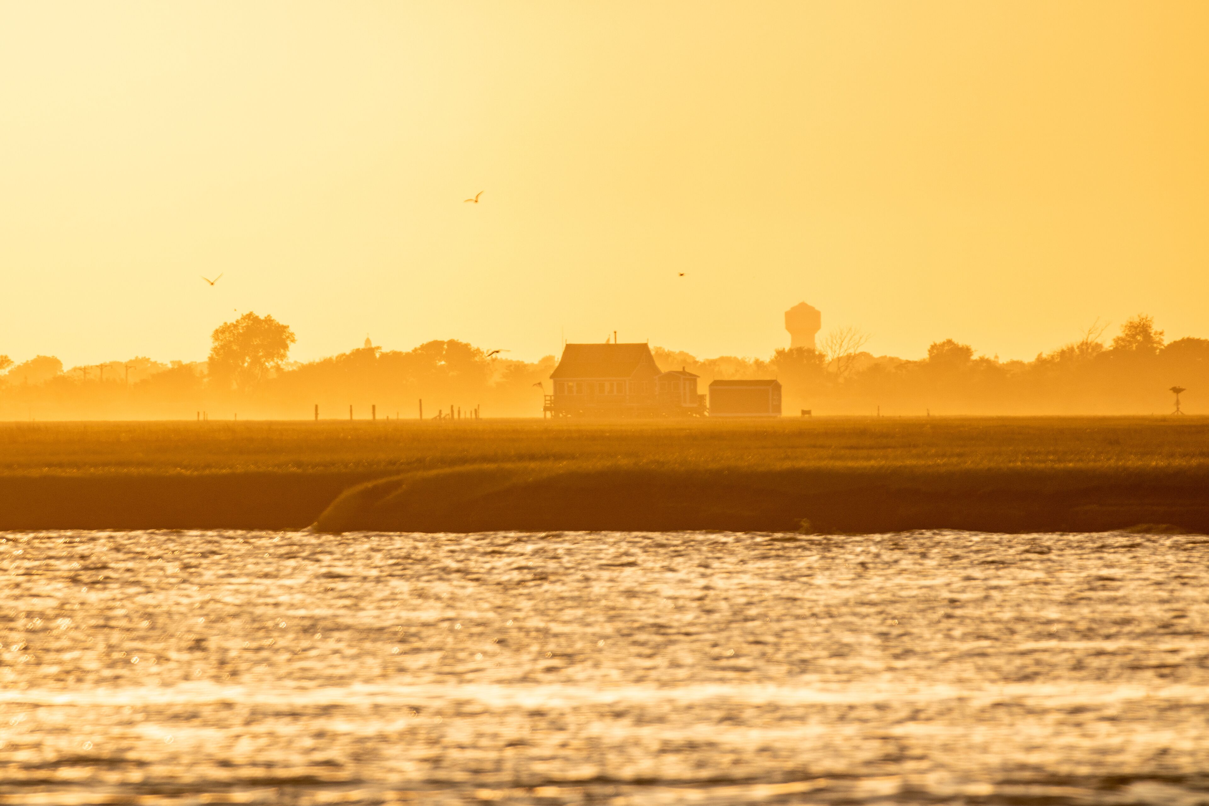 Golden light shining on a small bay house on the water at sunset. Long Island New York. 