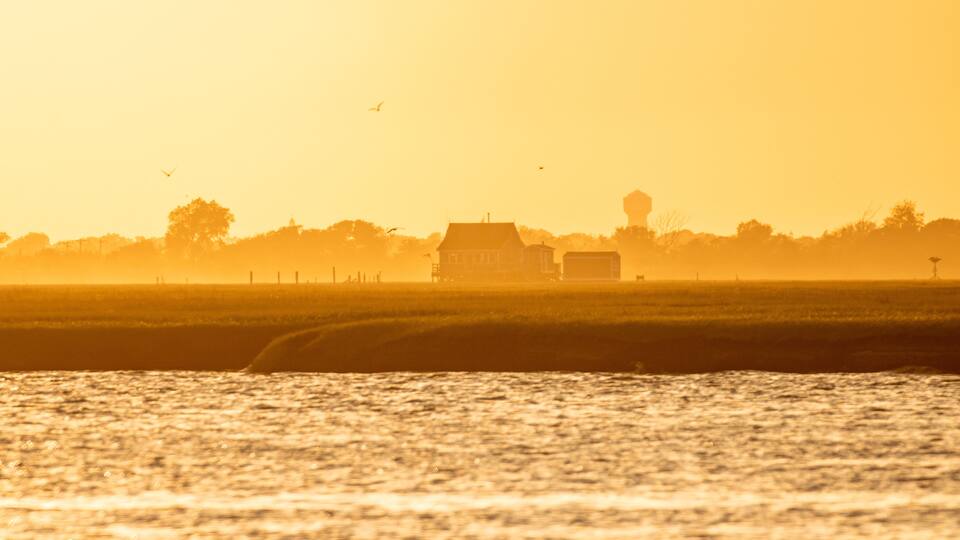 Golden light shining on a small bay house on the water at sunset. Long Island New York.