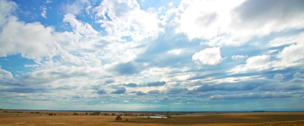 A vast open field under a partly cloudy sky.
