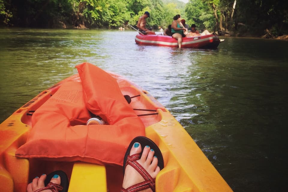 A yellow raft with orange cushions and a person wearing sandals.