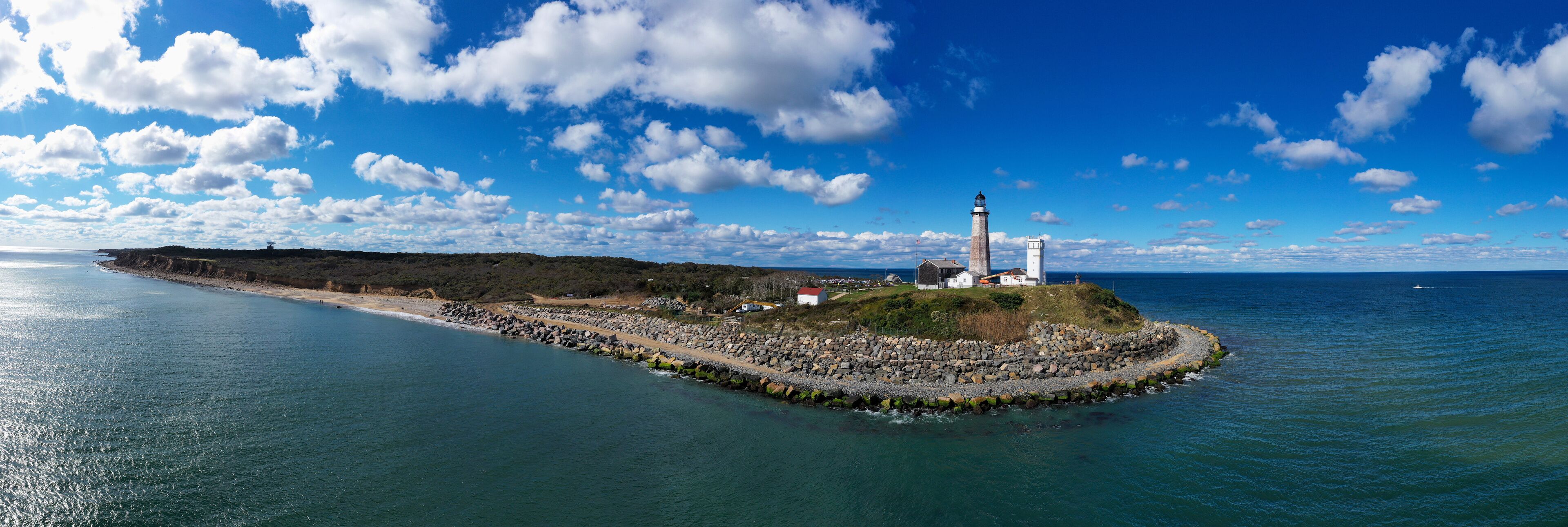 A lighthouse on a rocky island with a clear blue sky.
