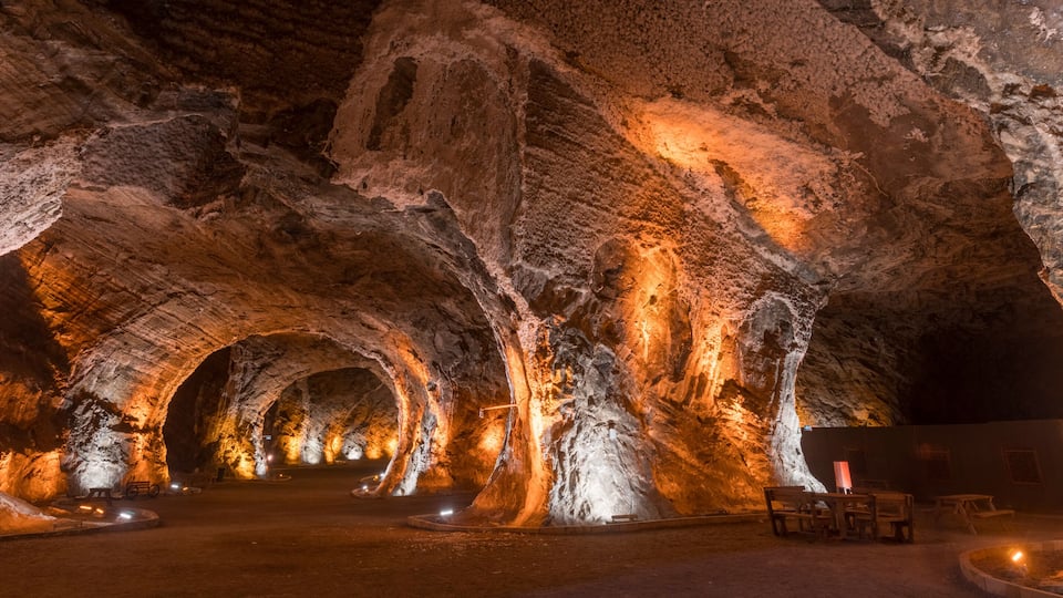 A cave with illuminated rock formations and benches.