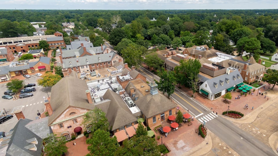 An aerial view of a small town with historic buildings, a church, and a dense forest in the background.