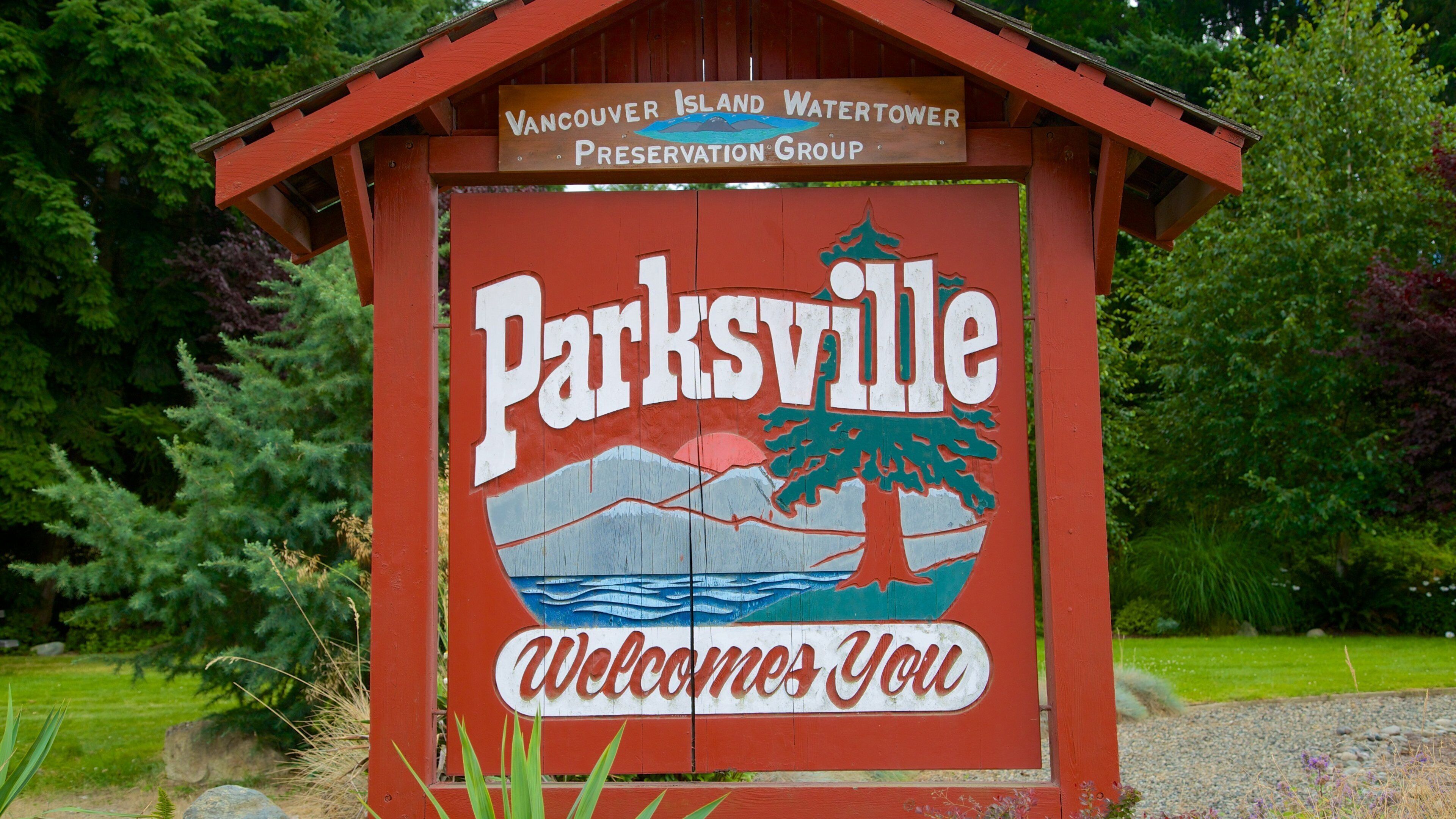 A wooden sign with 'Parksville' and 'Welcome You' written on it, along with a mountain and tree graphic.