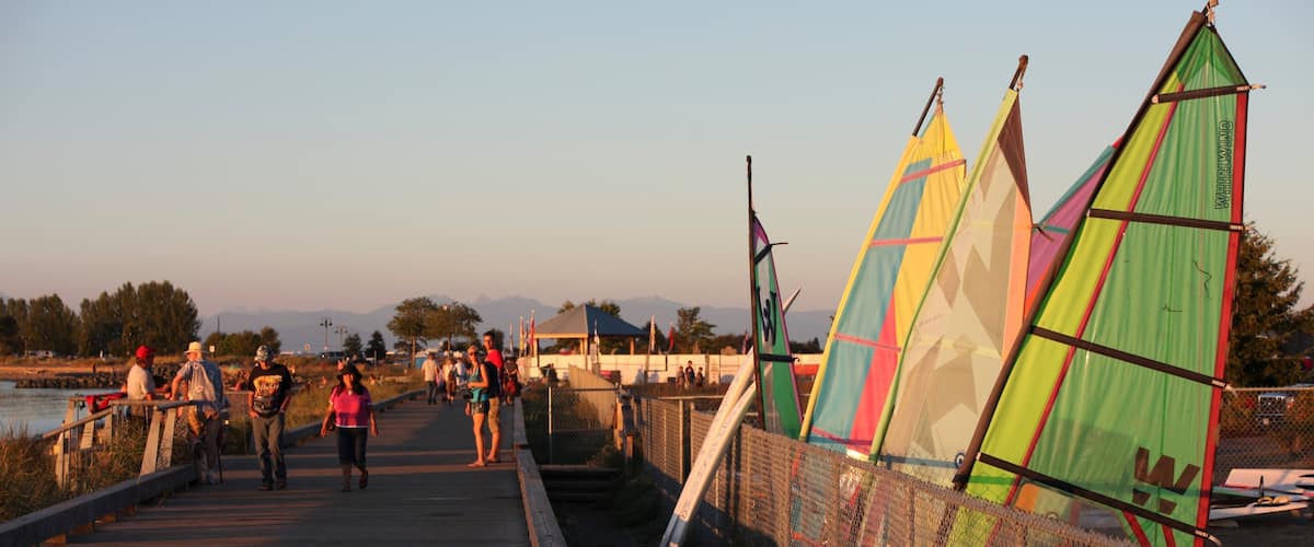 A wooden bridge with colorful sail-like structures on the right.