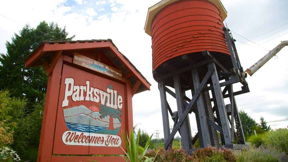 A red wooden sign with 'Parksville' and 'Welcome' written on it, next to a water tower.