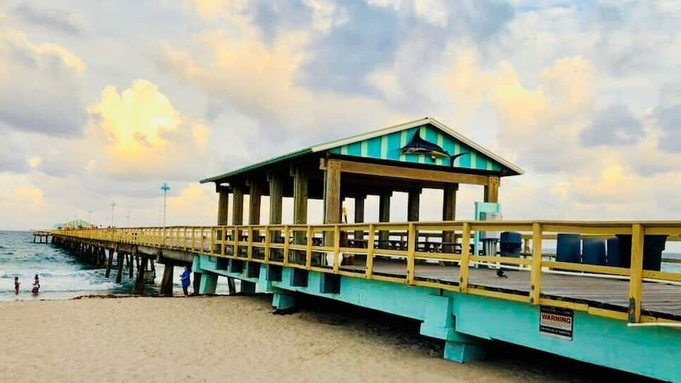A pier with a lifeguard tower and a warning sign.