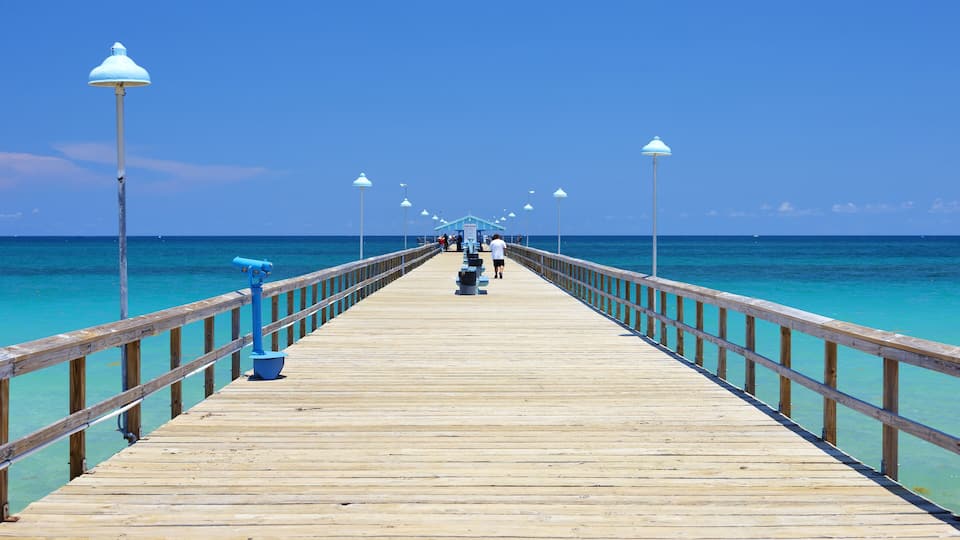 A wooden pier extending into turquoise waters, lined with evenly spaced street lamps.