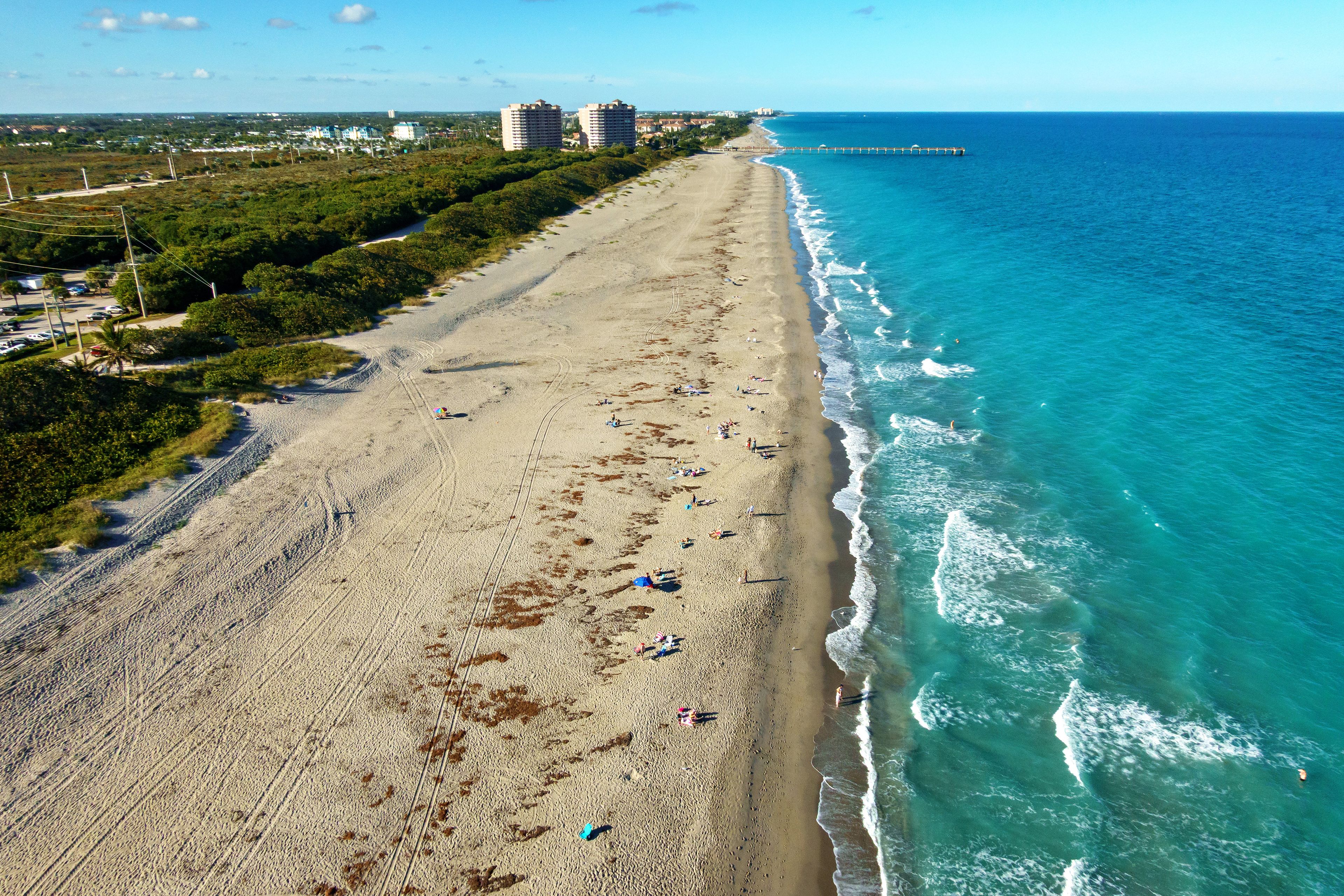 Una playa costera con vista despejada al océano, una orilla arenosa y un muelle distante.
