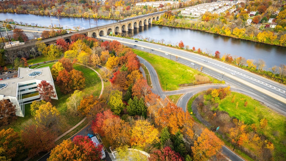 A river with a bridge, autumn foliage, and a highway.
