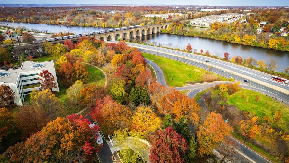 A river with a bridge, autumn foliage, and a highway.