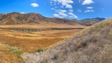 A dry valley with mountains in the background and a clear blue sky.
