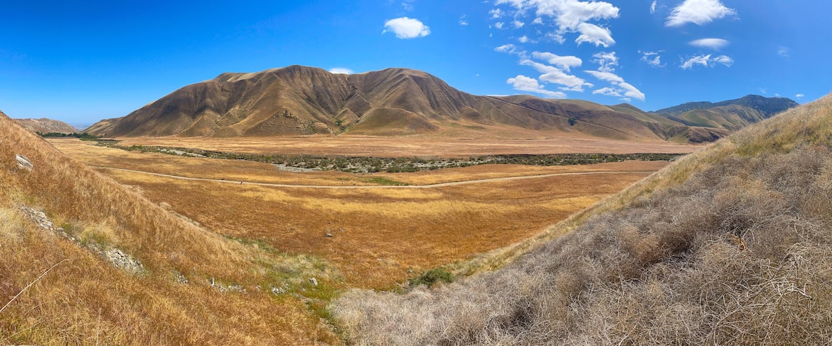 A dry valley with mountains in the background and a clear blue sky.