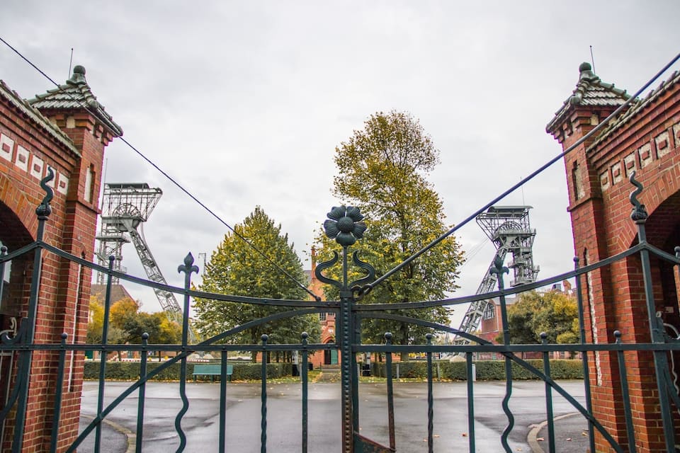 A wrought iron gate with a brick building in the background.