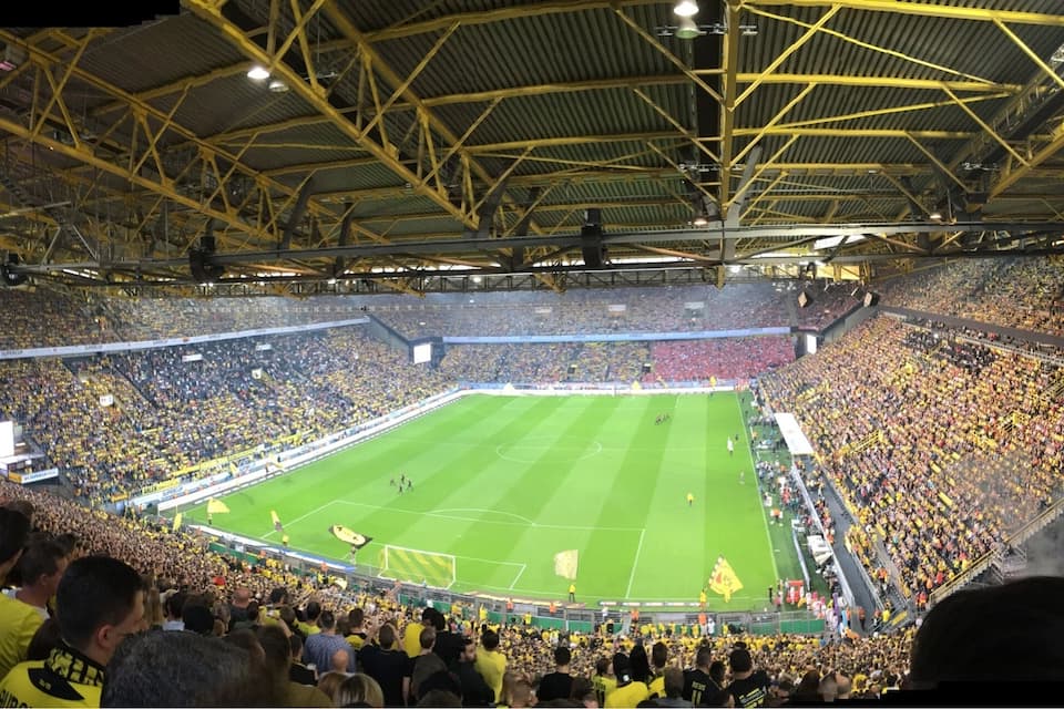 Um estádio amplo e coberto, repleto de espectadores.
