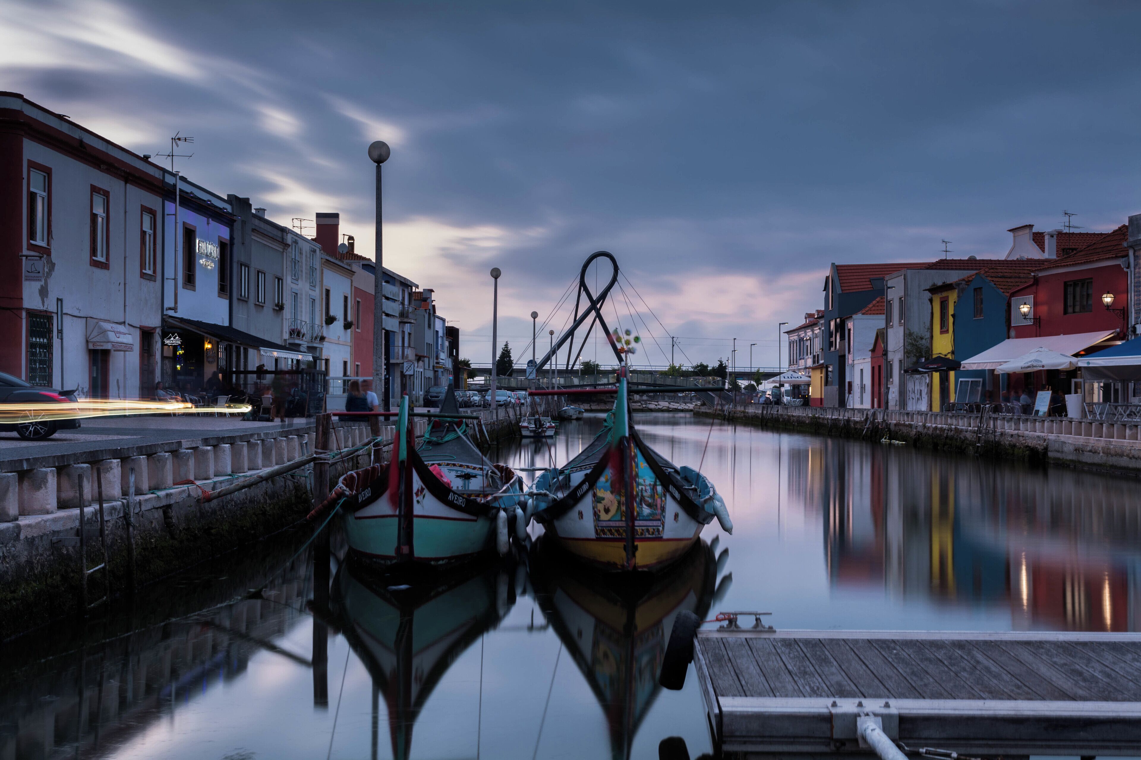 A calm waterfront with boats docked, colorful buildings, and a clear sky.