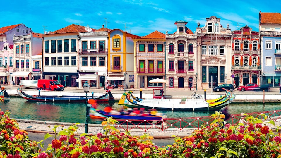 A canal with colorful boats, historic buildings, and vibrant flowers.