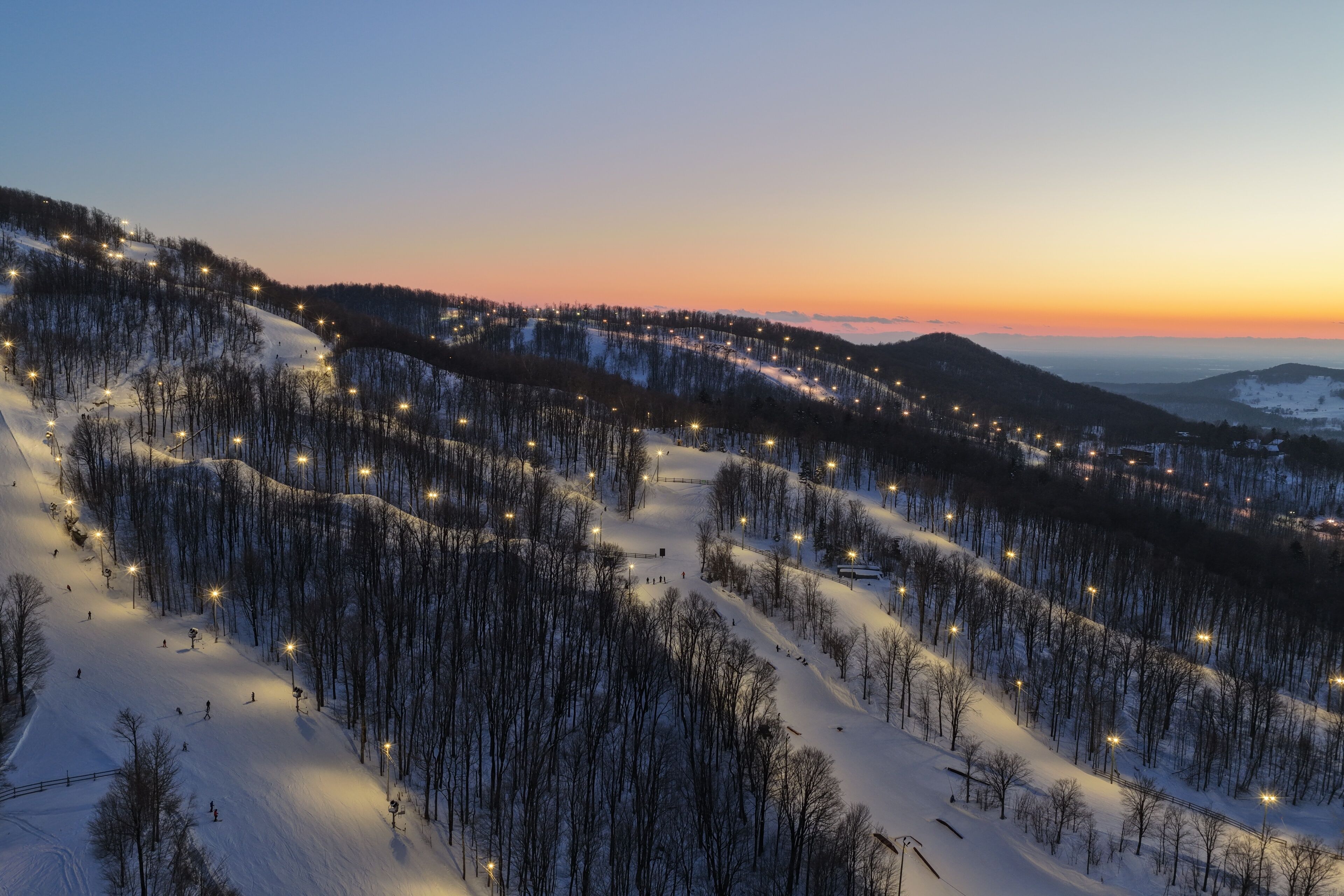 Aerial drone view of illuminated Bromont ski resort slopes at dusk, Quebec, Canada in winter. g.