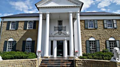 A historic building with a central entrance flanked by columns, stone walls, and decorative lion statues.