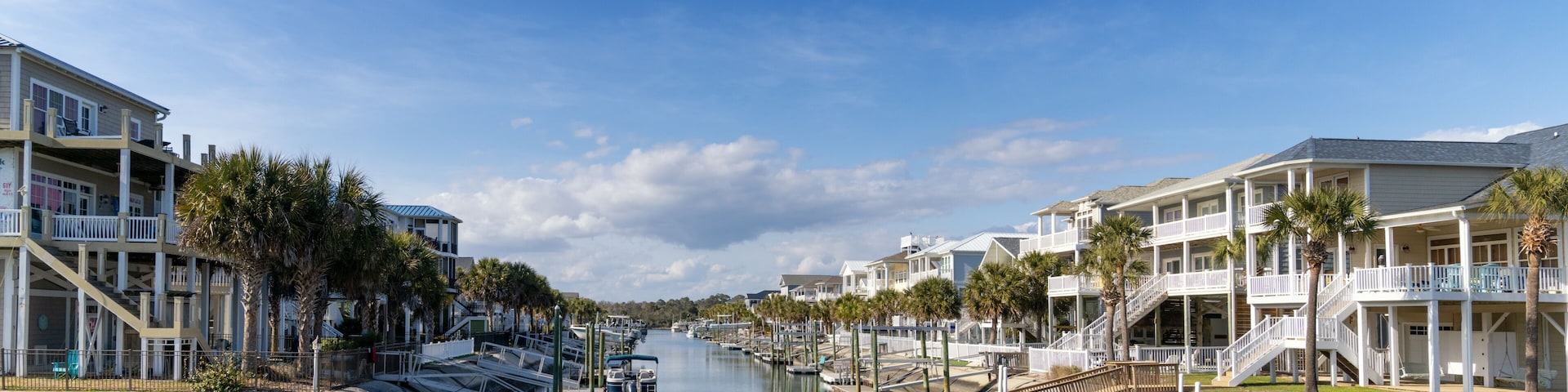 A canal lined with waterfront homes, a bridge, and a clear blue sky.