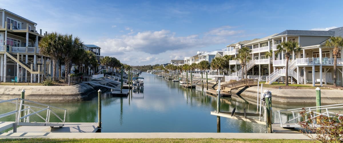 A canal lined with waterfront homes, a bridge, and a clear blue sky.