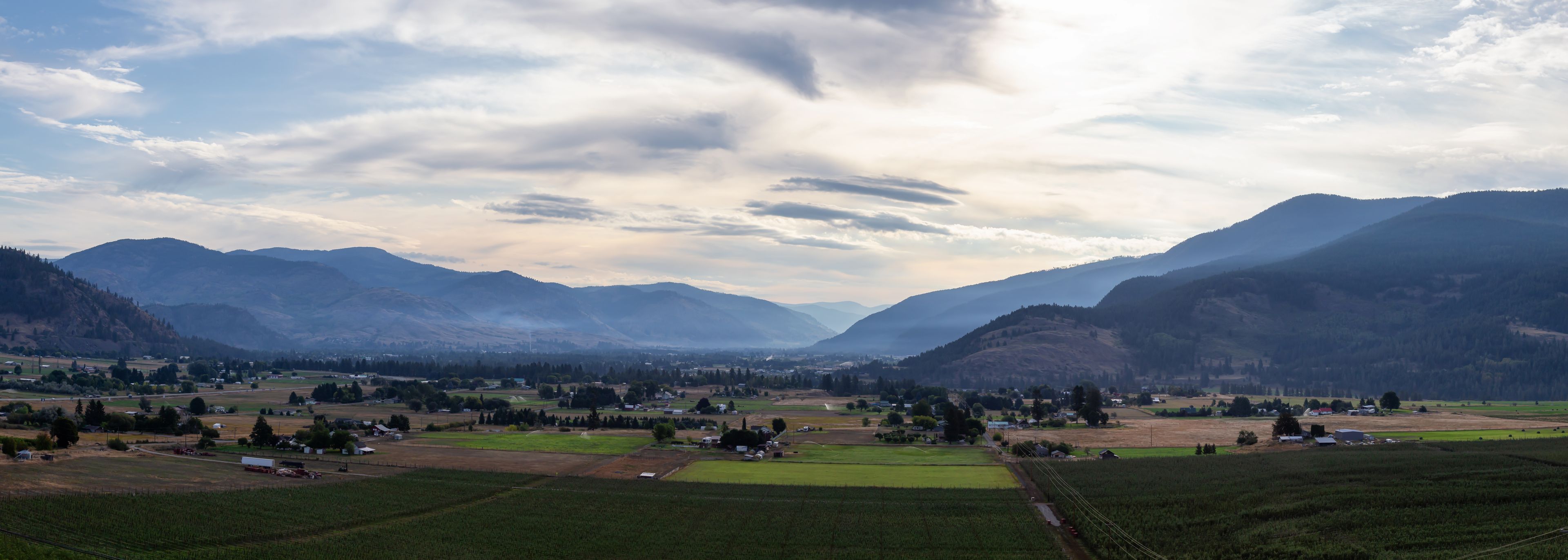 Ein Tal mit Bergen, Feldern und verstreuten Häusern.