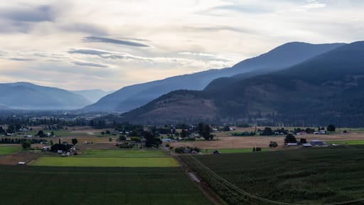 A valley with mountains, fields, and scattered buildings.