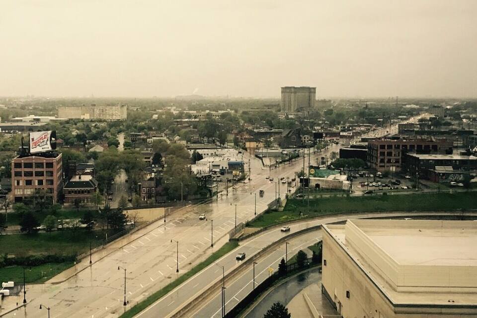 Paisagem urbana com um prédio grande com uma placa, uma rodovia e edifícios urbanos ao redor.
